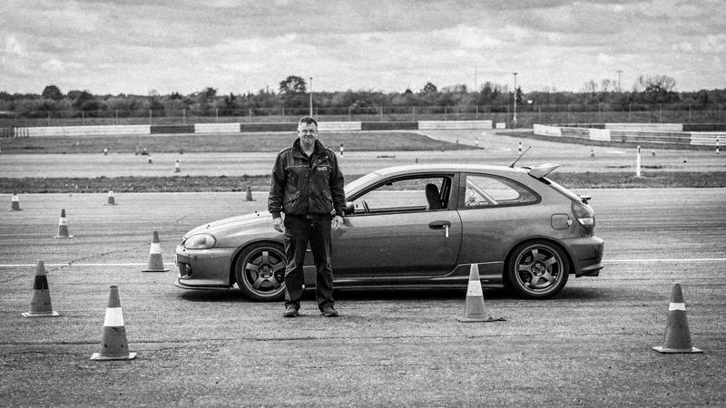 Instructor standing beside a training car on a closed course